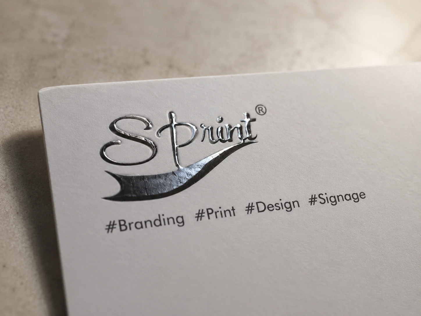 Close-up of glossy raised spot UV on the black Sprint logo of a white visiting card.